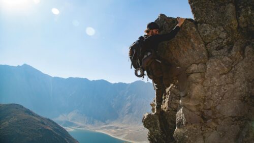 Adventurous Rock Climber Scaling High Mountain Peak 4K Wallpaper
