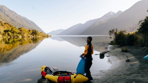 Adventurer Preparing Packraft at Serene Alpine Lake Desktop Wallpaper