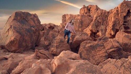 Woman Hiking Through Red Desert Rocks at Sunset Desktop Wallpaper