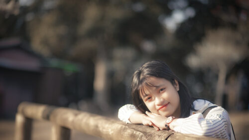 Beautiful Asian Girl Smiling Leaning on Wooden Fence 4K Wallpaper