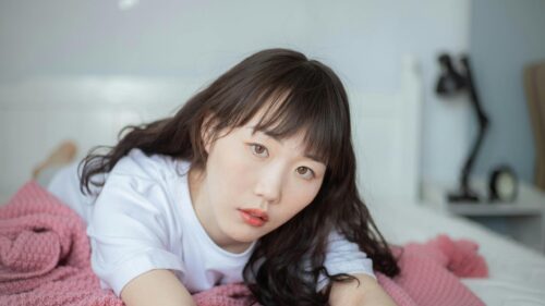 Stunning Asian Woman with Long Dark Hair Relaxing on Bed 4K Wallpaper