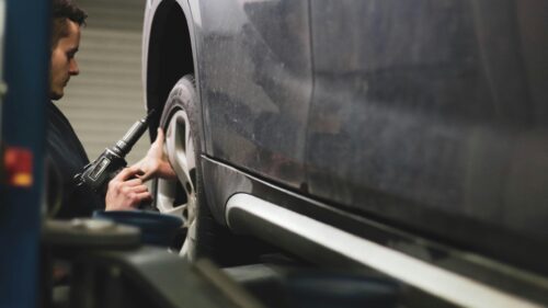 Mechanic Using Air Impact Wrench on Car Wheel Desktop Wallpaper