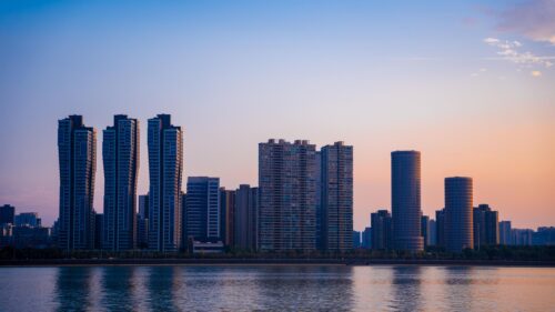 Stunning Modern City Skyline at Sunset Over River 4K Wallpaper