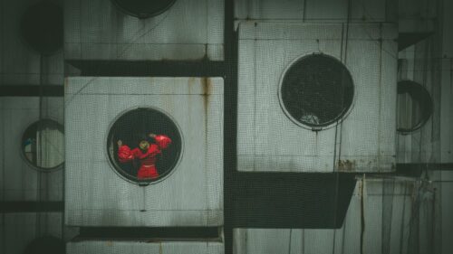Surreal Figure in Red Dress Behind Industrial Grids 4K Wallpaper