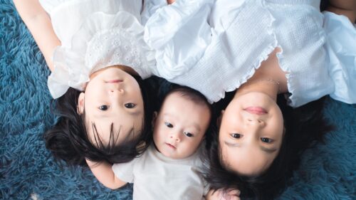 Three Adorable Siblings Lying Together on Blue Rug Desktop Wallpaper