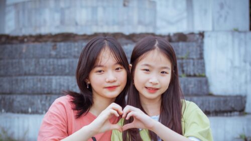 Two Cute Asian Friends Making Heart Shapes Desktop Wallpaper