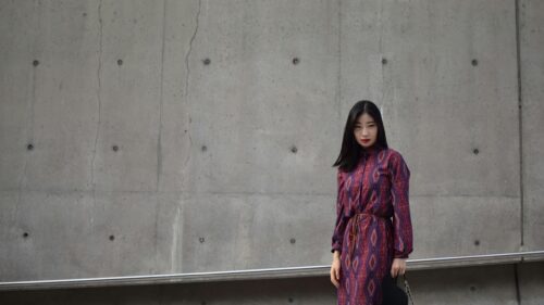 Elegant Woman in Red Patterned Dress Standing by Concrete Wall 4K Wallpaper