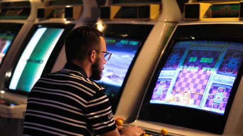 Man Playing Retro Arcade Games in Dark Retro Gaming Room 4K Wallpaper