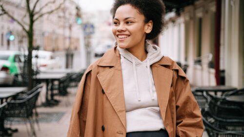 Smiling Woman in Trendy Beige Hoodie and Trench Coat Desktop Wallpaper