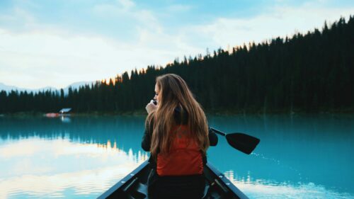 Woman Paddling Canoe on Serene Turquoise Lake 4K Desktop Wallpaper