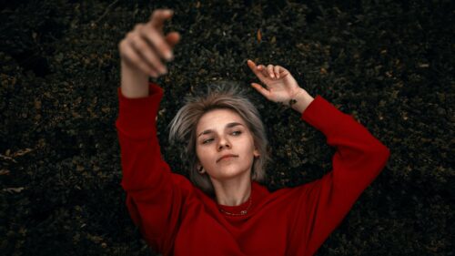 Aesthetic Blonde Girl in Red Sweater Lying on Nature Background 4K Wallpaper