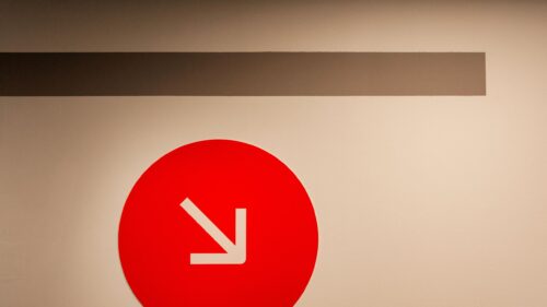 Minimalist Red Arrow Icon on Neutral Background 4K Wallpaper