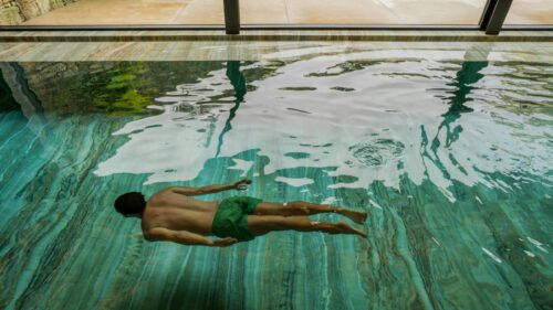 Man Swimming in Luxurious Indoor Pool High Resolution Desktop Wallpaper