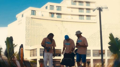 Three Men Wearing Matching Shirts Outside a Modern Resort Hotel 4K Wallpaper