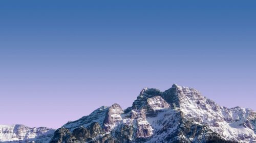 Majestic Snowy Mountain Peaks Under Clear Purple Sky 4K Wallpaper