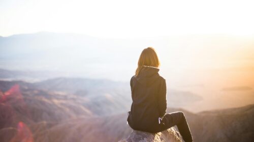 Woman Sitting on Mountain Peak at Sunset 4K Desktop Wallpaper