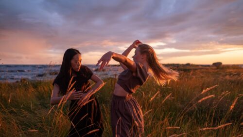 Two Women Dancing in Golden Hour Meadow 4K Wallpaper