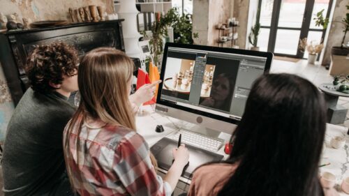 Three Creative Professionals Editing Photos on PC Desktop Wallpaper