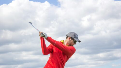 Golfer Mid-Swing Under Bright Cloudy Sky Desktop Wallpaper