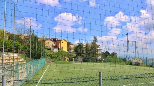 Sunlit Soccer Field in Italian Village Landscape Desktop Wallpaper
