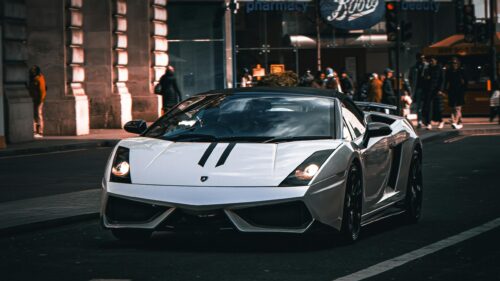 White Lamborghini Gallardo Driving Through City Street Desktop Wallpaper