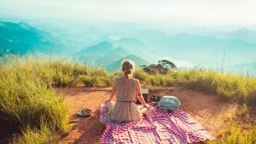 Woman Sitting on Red Picnic Blanket Overlooking Mountain View Desktop Wallpaper