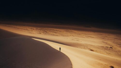 Lone Traveler Walking Across Golden Desert Dunes 4K Wallpaper