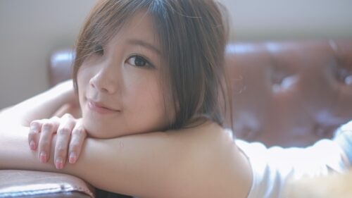 Beautiful Young Asian Woman Relaxing on Leather Sofa Desktop Wallpaper