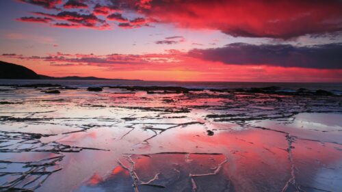Stunning Crimson Sunset over Rocky Coastal Shore 4K PC Wallpaper