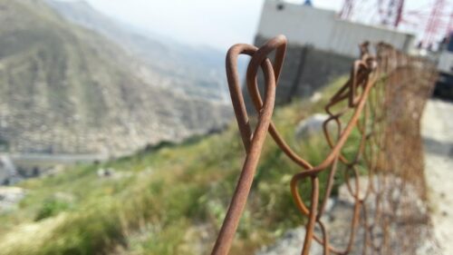 Macro View of Rusted Metal Fence on Mountain Hillside Desktop Wallpaper