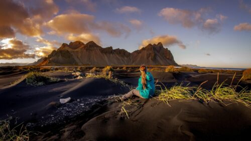 Woman Sitting on Vestrahorn Black Sand Beach Iceland 4K Wallpaper