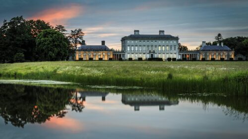 Majestic Stately Mansion at Sunset with Water Reflection 4K Wallpaper