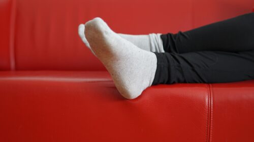 Relaxing Person Resting Feet on Red Leather Sofa 4K Wallpaper