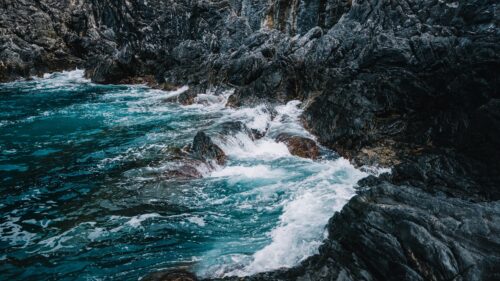 Stunning Turquoise Ocean Waves Crashing Against Dark Coastal Rocks PC Wallpaper