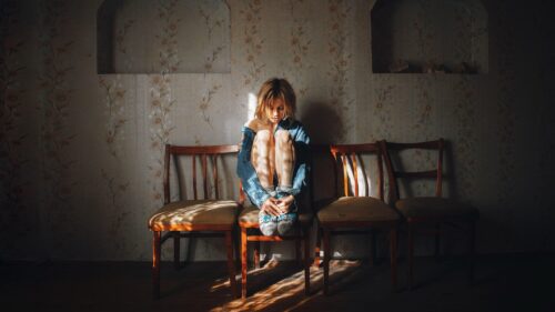 Melancholic Girl Sitting on Wooden Chairs in Sunlit Room PC Wallpaper