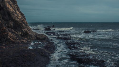 Moody Ocean Waves Crashing Against Jagged Coastal Cliffs Desktop Wallpaper