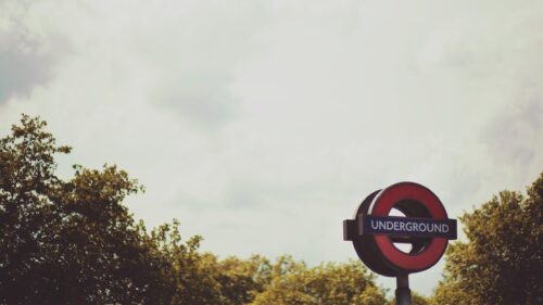 Iconic London Underground Sign against a Cloudy Sky Desktop Wallpaper