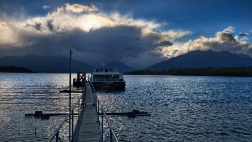 Dramatic Lake Pier with Boat and Moody Stormy Clouds 4K Wallpaper