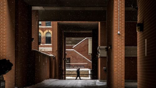 Solitary Pedestrian Walking Through Snow Covered Brick Alleyway PC Wallpaper