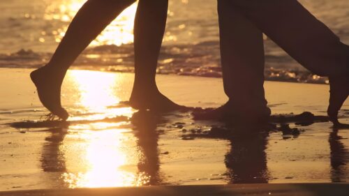 Romantic Couple Walking on Beach at Golden Sunset Desktop Wallpaper