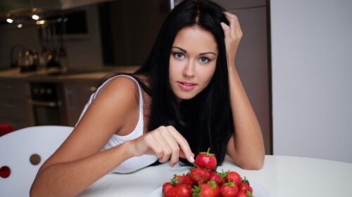 Beautiful Woman Eating Fresh Strawberries in a Modern Kitchen PC Wallpaper
