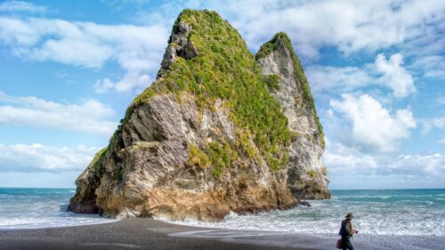 Stunning Coastal Rock Formation with Traveler on Black Sand Beach PC Wallpaper