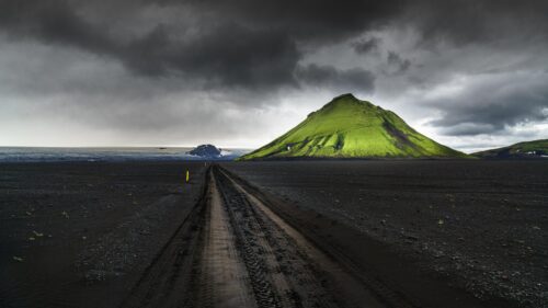 Dramatic Icelandic Landscape with Vibrant Green Mountain and Black Sand Road 4K Wallpaper