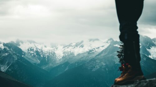 Hiker Standing Before Majestic Snow Capped Mountain Peaks Desktop Wallpaper