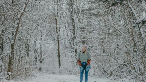 Woman Standing in a Snowy Forest Winter Scene 4K Desktop Wallpaper