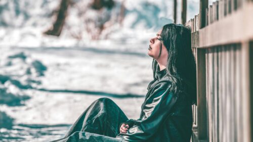 Melancholic Girl Leaning on Wooden Fence in Snowy Winter 4K Wallpaper
