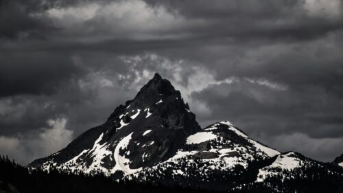 Dramatic Snowy Mountain Peak Under Stormy Dark Clouds 4K Desktop Wallpaper