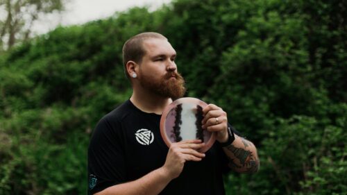 Professional Disc Golfer Holding Artistic Dyed Disc 4K Wallpaper