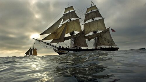 Majestic Tall Ship Sailing Under Cloudy Skies Desktop Wallpaper