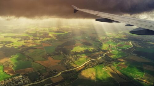 Aerial View of Farmland and River Beneath Airplane Wing 4K Wallpaper